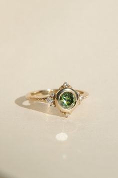 a close up of a ring with a green stone in it on a white surface