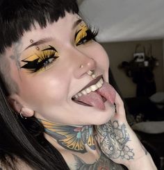 a woman with tattoos on her chest and yellow eyeshadow is posing for the camera