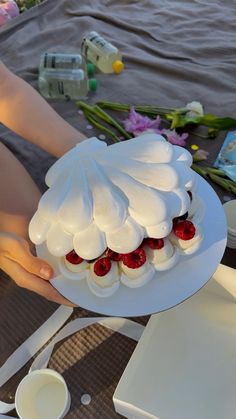 a person holding a cake with strawberries on it in front of other food items