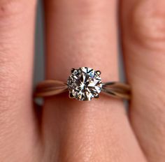 a close up of a person's hand with a diamond ring on their finger