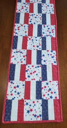 a red, white and blue quilted table runner on a wooden floor with an american flag design