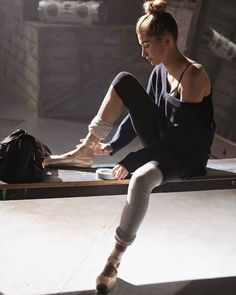 a woman sitting on the floor with her leg in cast and holding onto an object