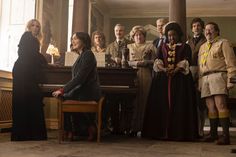 a group of people standing around a piano