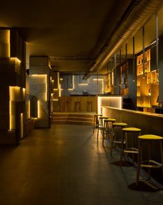 a dimly lit bar with yellow stools and shelves filled with bottles on the wall