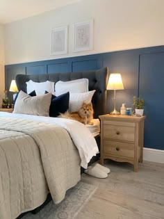 a dog laying on top of a bed next to two nightstands with lamps in the corner