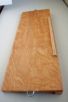 a wooden cutting board sitting on top of a white counter next to a knife holder