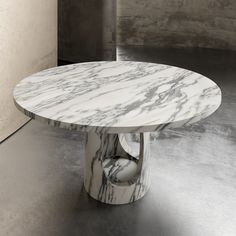 a white marble table sitting on top of a metal floor next to a gray wall