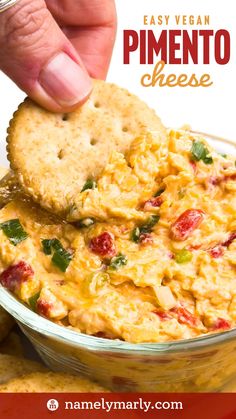 a hand dipping a cracker into a bowl of cheesy dip with the words easy vegan pimentoo cheese