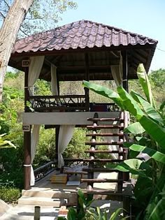 a wooden gazebo sitting in the middle of a lush green forest