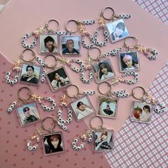 a bunch of keychains with pictures on them sitting on a pink tablecloth