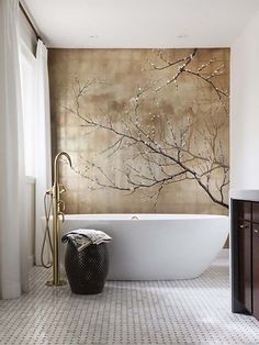 a white bath tub sitting in a bathroom next to a wall with a painting on it