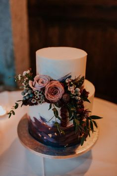 a white and blue wedding cake with flowers on the top is sitting on a table