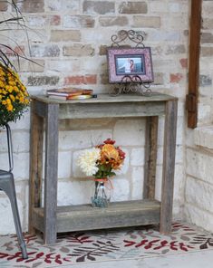 a small table with flowers on it and a chair next to it in front of a brick wall