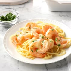 pasta with shrimp and parsley on a white plate next to two bowls of seasoning