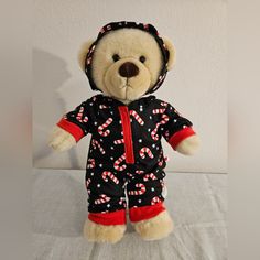 a teddy bear wearing a black and red outfit with candy canes on it's chest