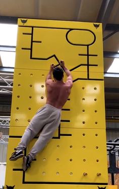 a man climbing up the side of a yellow sign in a building with an advertisement on it