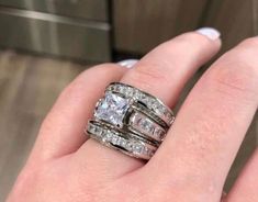 a woman's hand with two wedding rings on top of her finger and the ring is