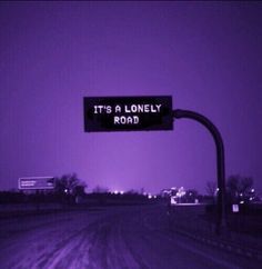 a street sign that says it's a lonely road in front of a purple sky