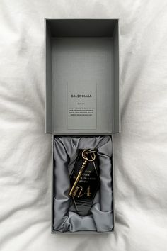 an open box with a key in it sitting on a bed next to a white sheet