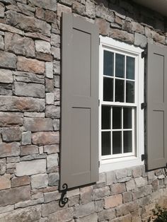 a stone building with two windows and shutters