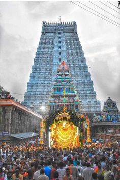 people are standing in front of an elaborate structure with lights and decorations on the sides