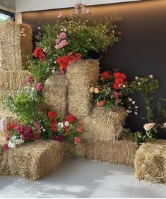 hay bales filled with flowers and plants in front of a large wall mounted window