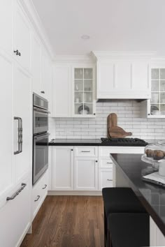 a kitchen with white cabinets and black counter tops, along with an island in the middle