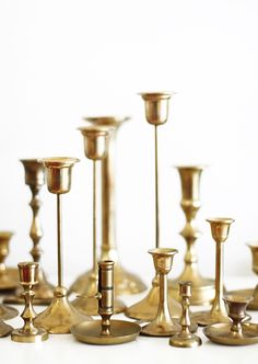 a group of gold candlesticks sitting on top of a white table next to each other