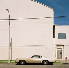 an old white car parked in front of a building on the side of the road