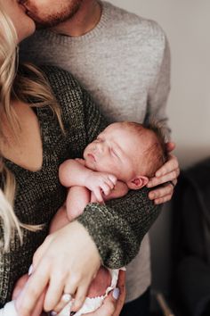 a man and woman holding a baby in their arms