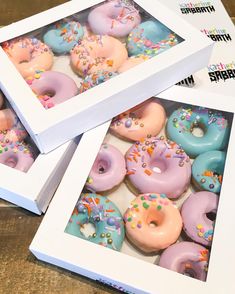 three boxes filled with assorted donuts on top of a wooden table