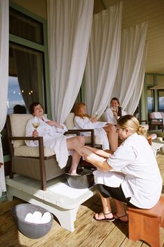 a group of women sitting on top of a wooden bench in front of a window