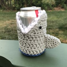 a crocheted cup cozy with a can holder attached to the top, sitting on a table outside