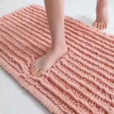 a person standing on top of a pink bath mat next to a white tile floor