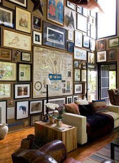 a living room filled with furniture and lots of framed pictures on the wall above it