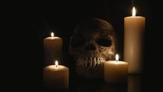 three candles are lit next to a skull