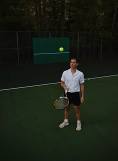 a man standing on a tennis court holding a racquet and ball in his hand