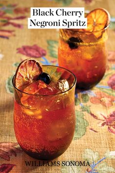 two glasses filled with drinks sitting on top of a floral table cloth next to each other