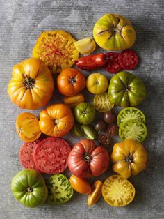 there are many different types of tomatoes on the table and one is red, green, yellow, and orange