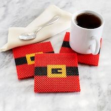 three red coasters with black and yellow designs next to a cup of coffee