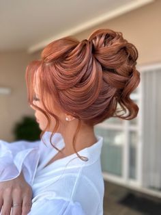 a woman with red hair is wearing a white shirt and has her hand on her shoulder