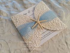 a wedding card with a starfish on it is laying on a lace tablecloth