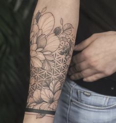 a woman with a tattoo on her arm holding onto a black and white flower of life