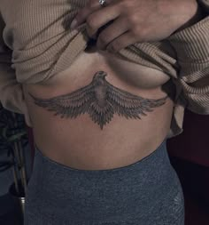 a woman's stomach with a bird tattoo on her belly and the bottom part of her stomach