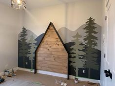 a room that has some trees painted on the wall and is being decorated with paint