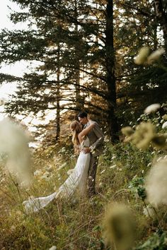 a bride and groom kissing in the woods