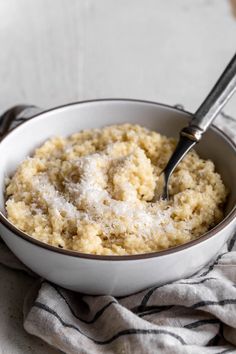 a white bowl filled with oatmeal on top of a striped cloth next to a spoon