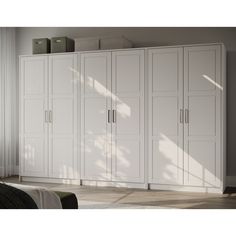 a large white closet with many doors and drawers on it's sides, next to a bed