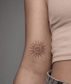 a woman's arm with a small sun tattoo on the back of her left arm