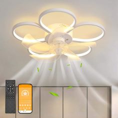 a ceiling fan with lights and remote controls on the wall next to an orange phone